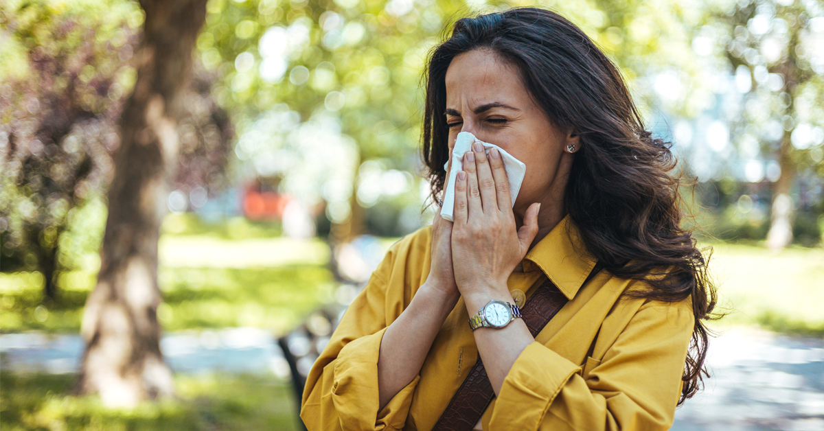 a woman sneezes into a tissue as fall allergies are in season